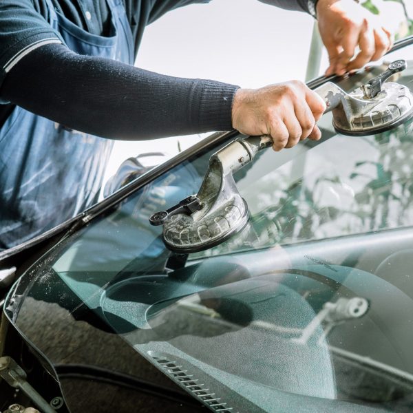 Mechanics man changing the broken windshield and automobile wind Mechanics man changing the broken windshield and automobile windshield or windscreen replacement of white car in Auto Repair Shop